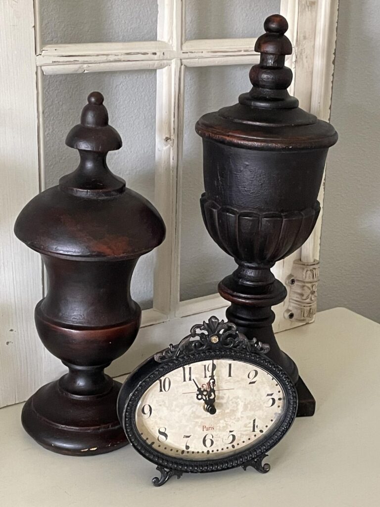 A clock in front of two decorative finial statues. 