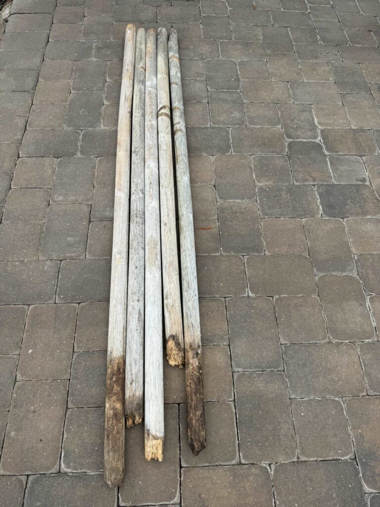 Five used tree Stakes laying on a driveway. 