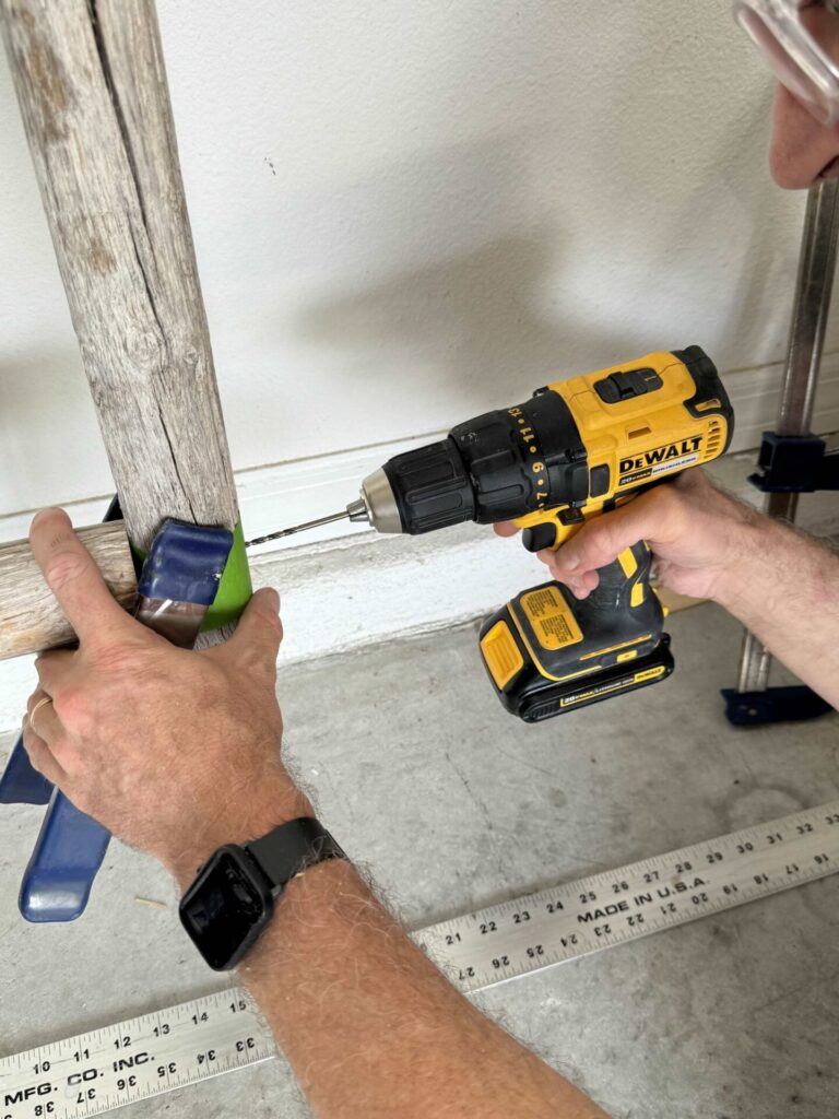 A man using a drill to screw into a DIY towel ladder. 