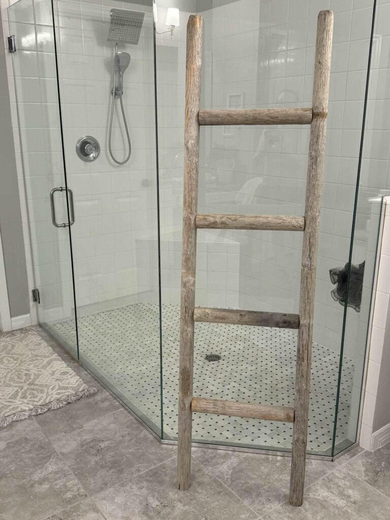 A DIY towel ladder against a glass shower. 