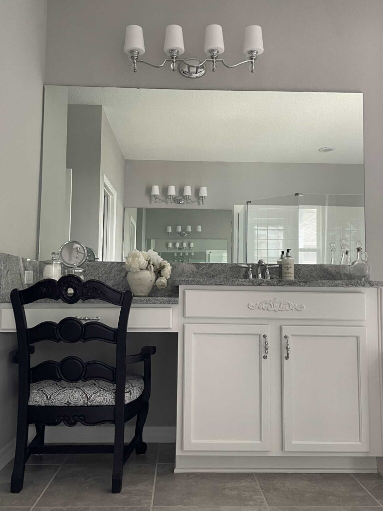 White bathroom cabinet with a plain mirror over it. 