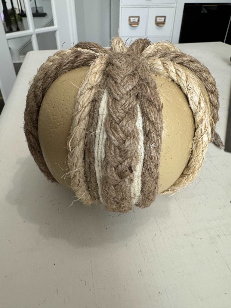 A pumpkin with braided strip of twine around it. 