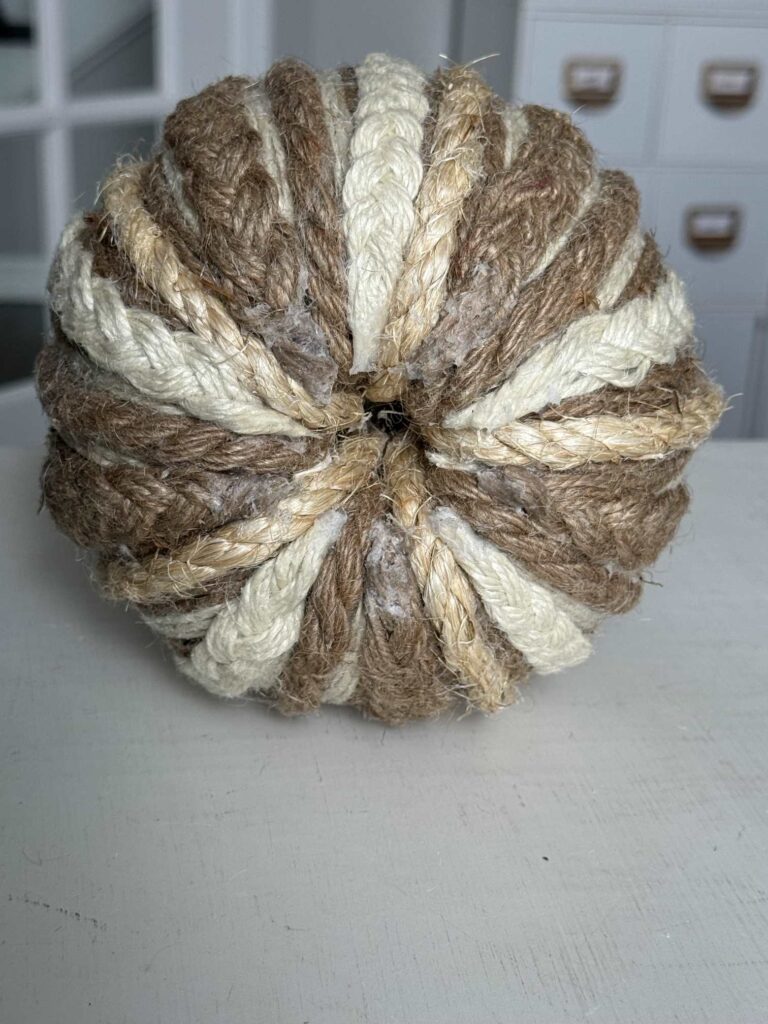 The bottom of a pumpkin wrapped with rope and twine. 