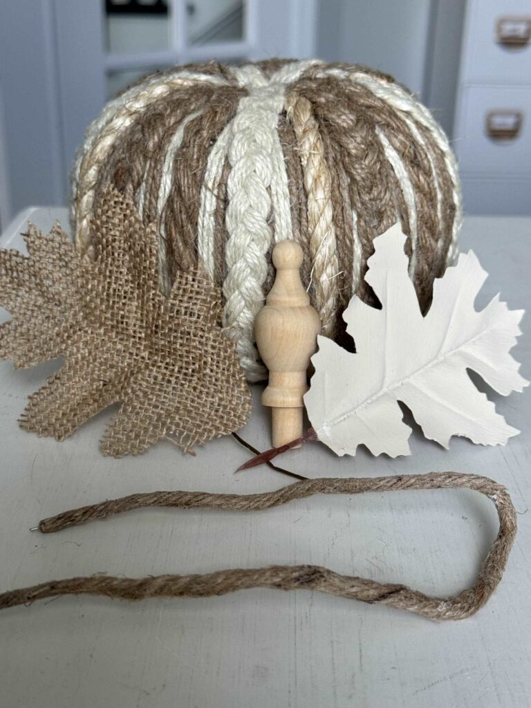 A pumpkin with two leaves, a wood finial, and wired jute. 