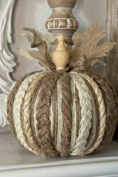 A pumpkin covered with neutral rope and twine with a wood finial stem.