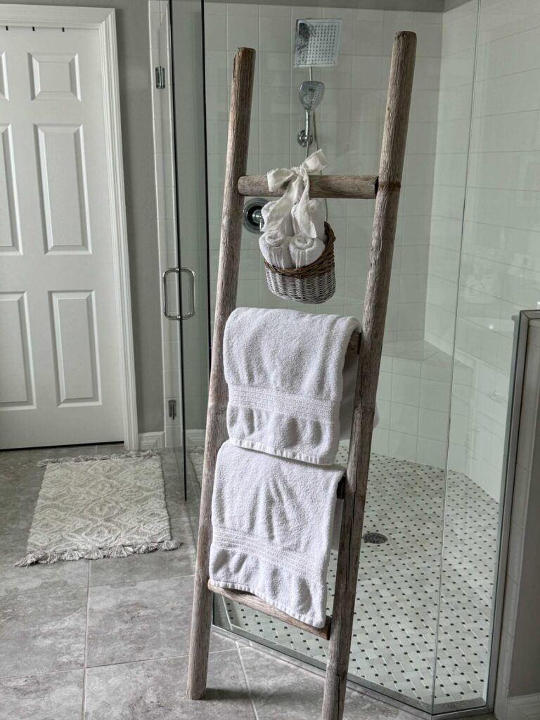 A DIY towel ladder with two white towels and a basket of wash clothes. 