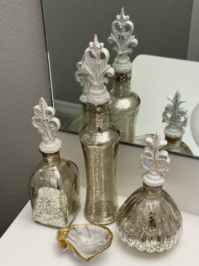 Three mercury glass canisters with a shell trinket tray in front of them. 