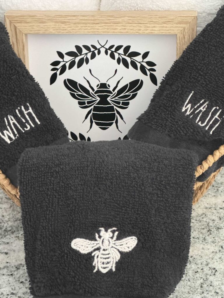 Black washcloths with a bee and the word wash embroidered on them. 