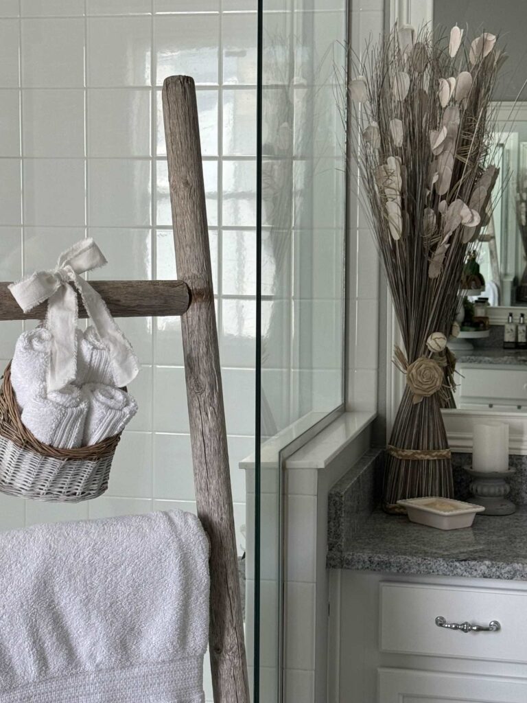 A tall skinny dried flower arrangement decorating a bathroom counter. 