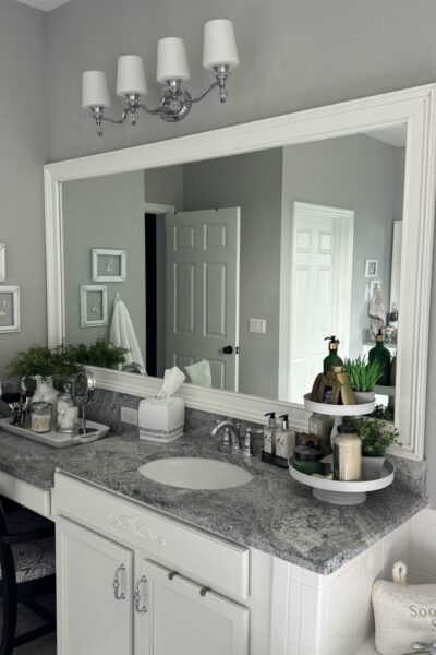 A large bathroom mirror with a DIY white frame around it.