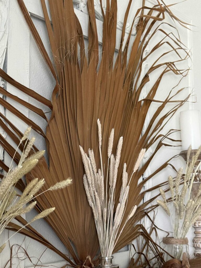 A dried brown palm frond displayed over a fireplace is perfect for early fall decorating. . 