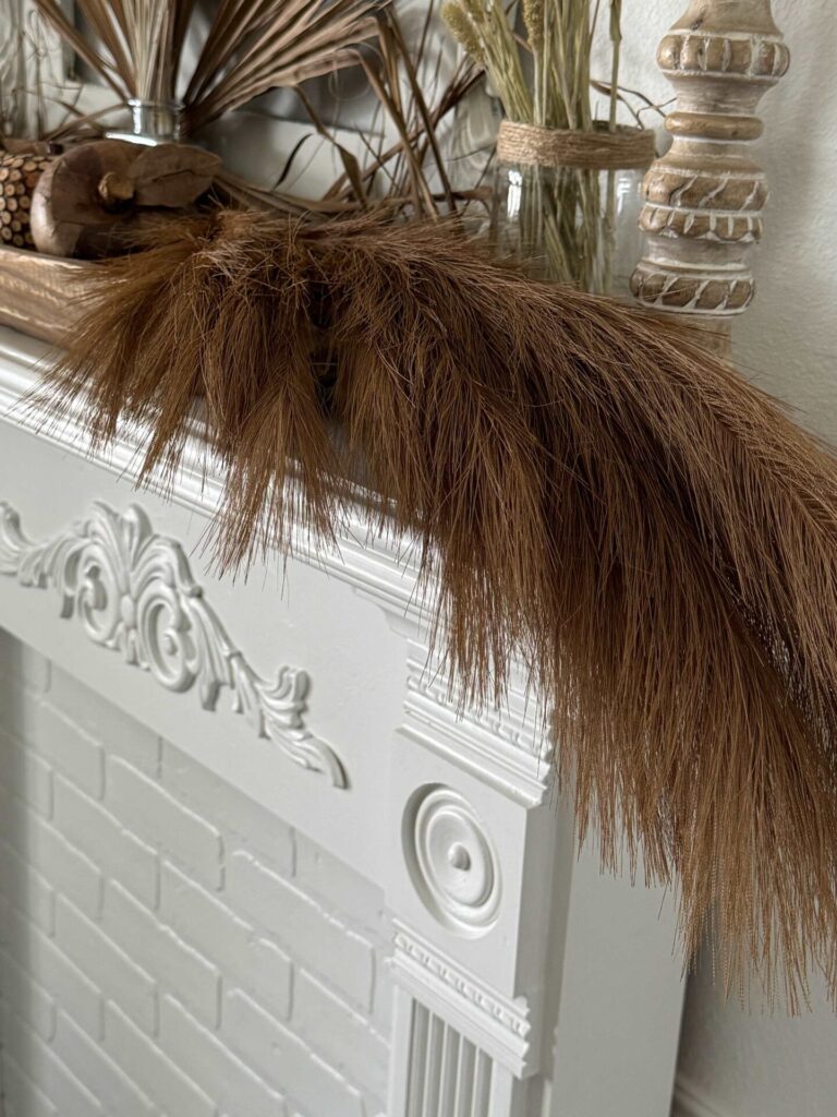 Brown pampas grass laying over a mantel is a good fall decorating idea.