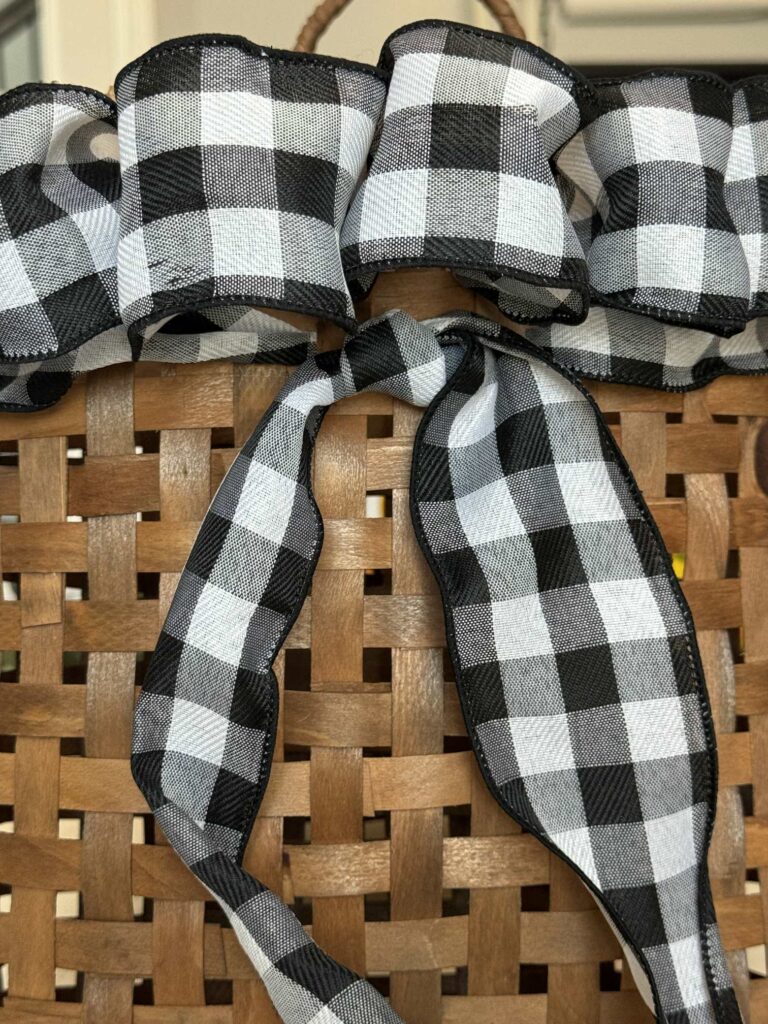 Black and white buffalo check ribbon tied on the front of a basket. .