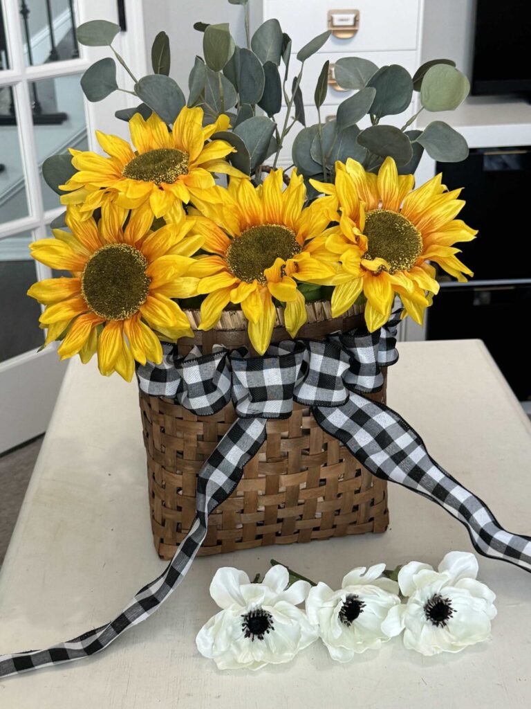 Step three to make a DIY sunflower wreath is to add sunflowers and eucalyptus inside a basket.