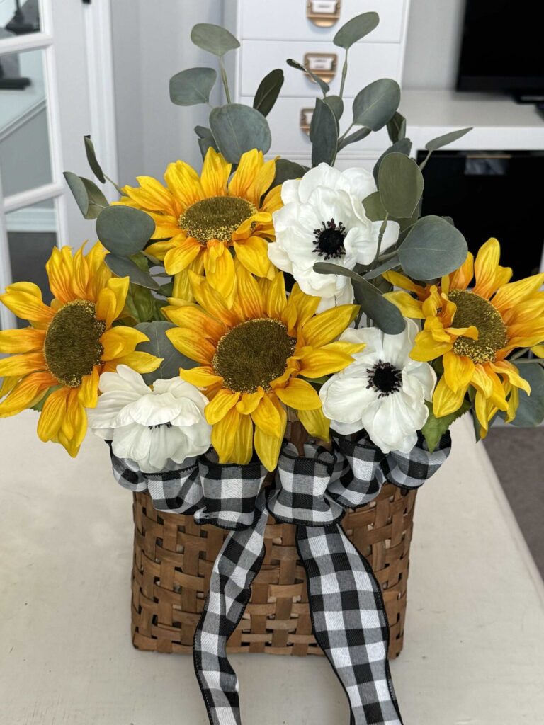 Sunflowers, eucalyptus, and white poppies inside a basket.