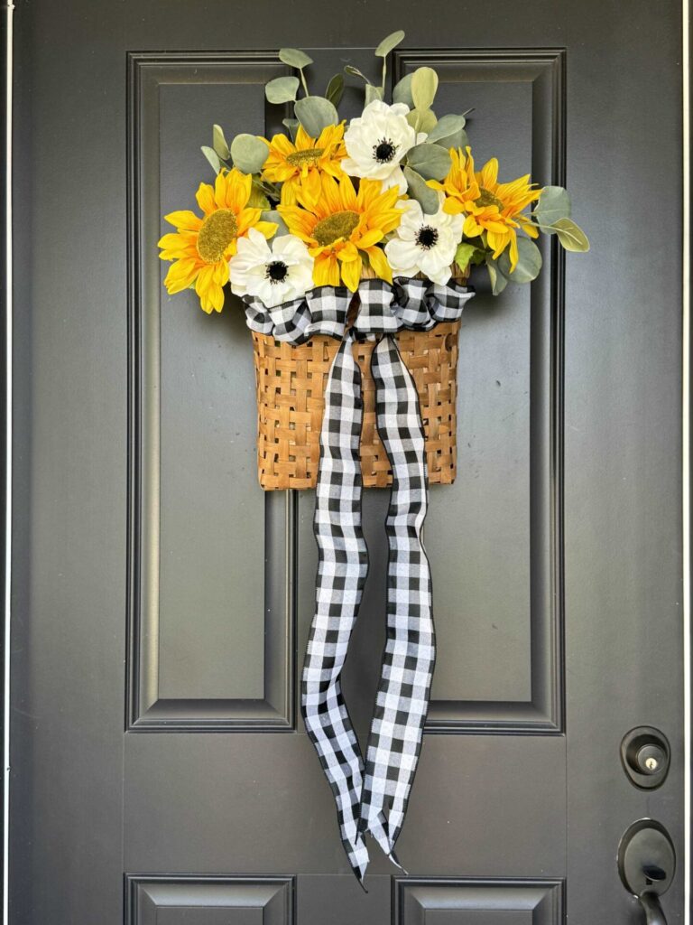 A DIY sunflower wreath with a long ribbon hanging on a front door. 