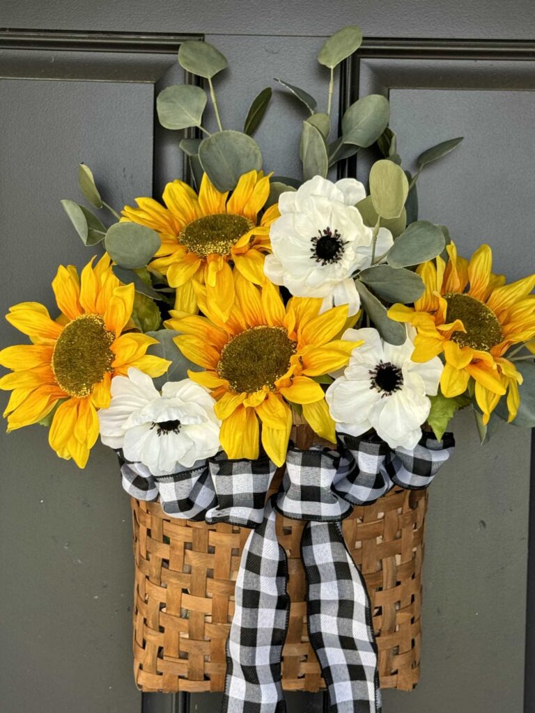 A DIY sunflower wreath hanging on a black door. 