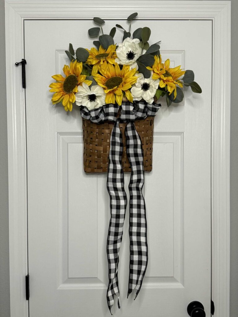 A DIY sunflower wreath hanging on a white door.