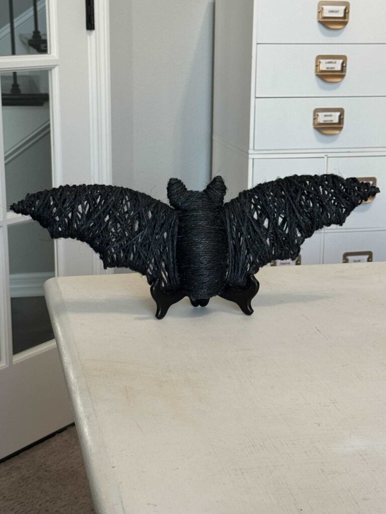 A DIY Halloween bat displayed on a plate holder. 