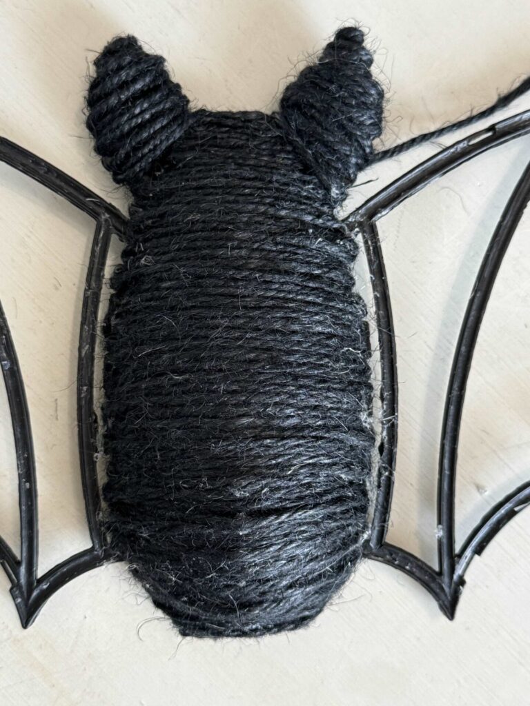 A DIY Halloween bat with it's plastic body covered in black twine. 