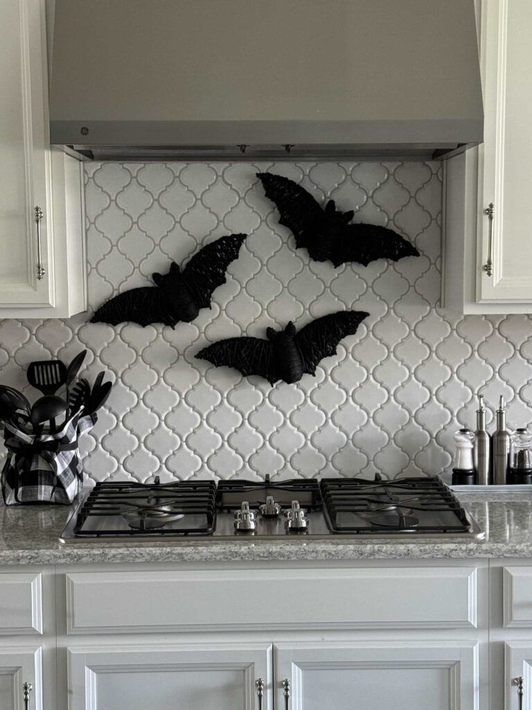 Three black bats hanging above a kitchen stove. 