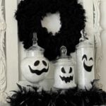 Three apothecary jars transformed into ghosts with a black wreath behind them.