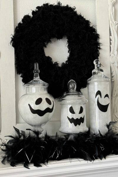 Three apothecary jars transformed into ghosts with a black wreath behind them.