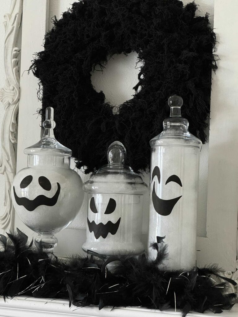 Three ghost apothecary jars in front of a black wreath. 