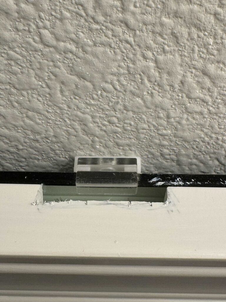 A plastic clip behind a framed mirror. 