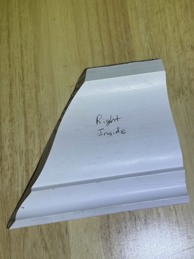 Example scrap of crown molding cut as right inside corner marked and oriented as it will mount to the wall