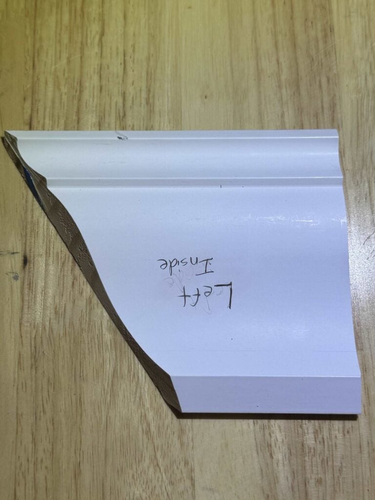 Example scrap of crown molding cut as left inside corner marked and oriented as it will mount to the saw