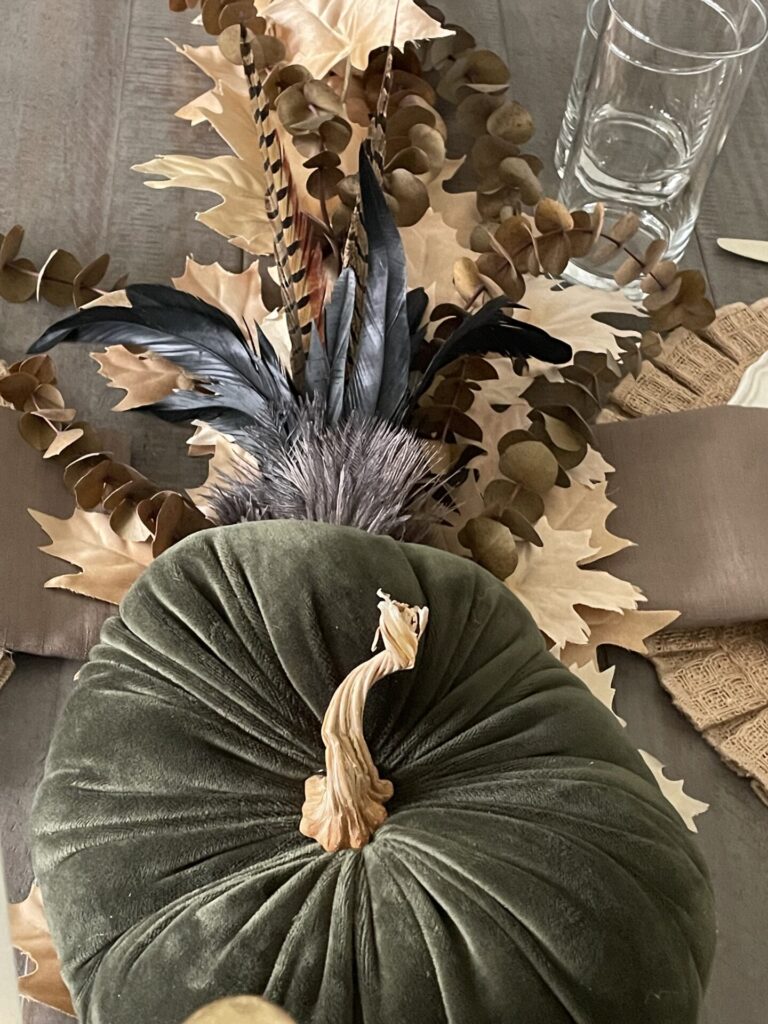 A velvet pumpkin with fall foliage and feathers. 