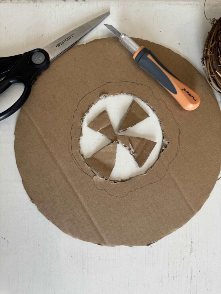 A cardboard circle with a hole in the middle, scissors and a craft knife. 