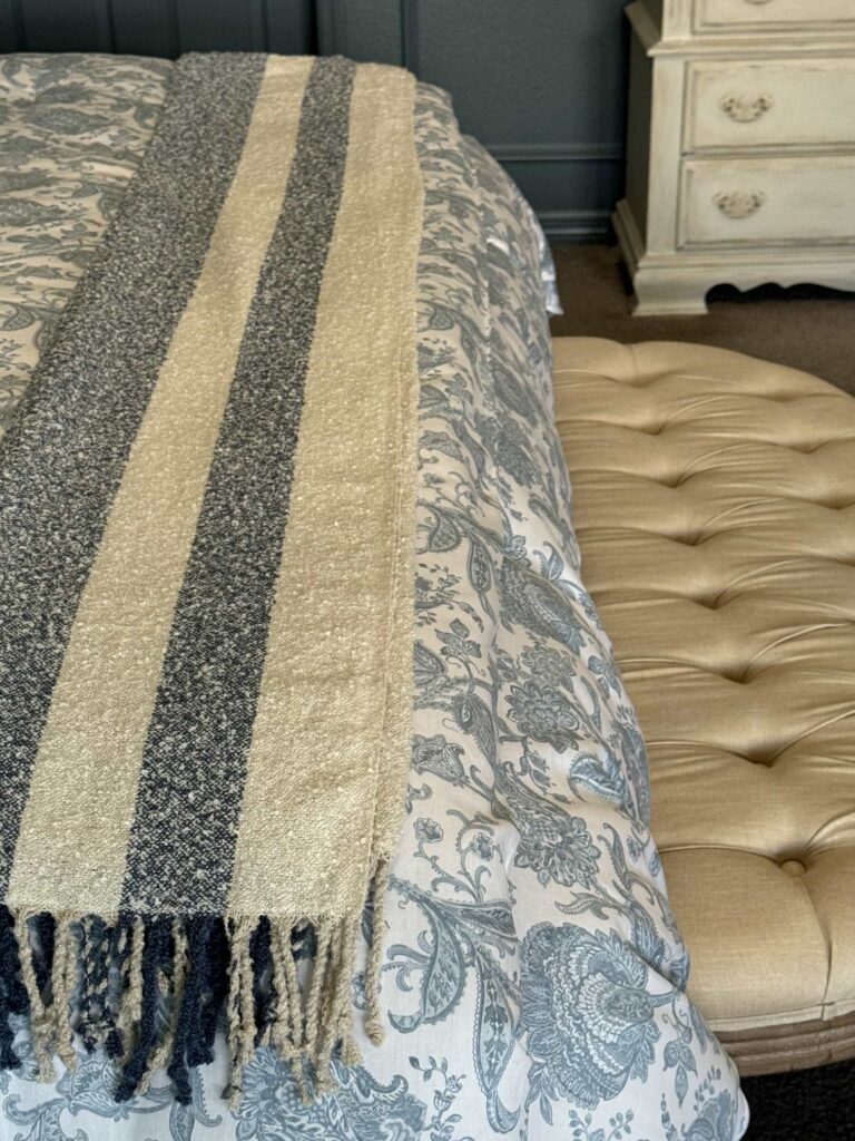 A blue and white stripped throw blanket on the end of a bed. 