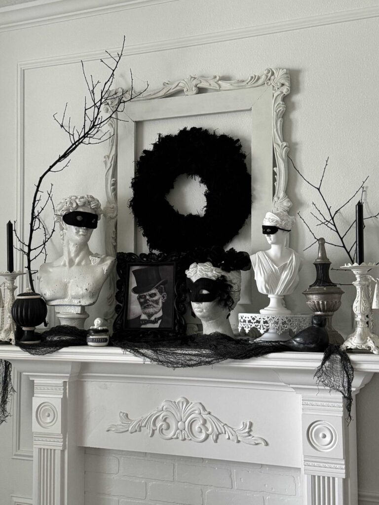 A Halloween mantel decorated with statues wearing masks. 