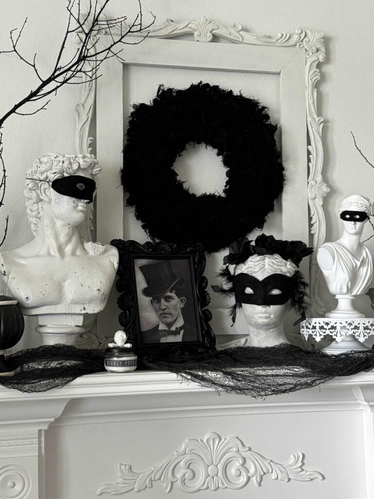 A mantel decorated for Halloween with statues wearing masks. 