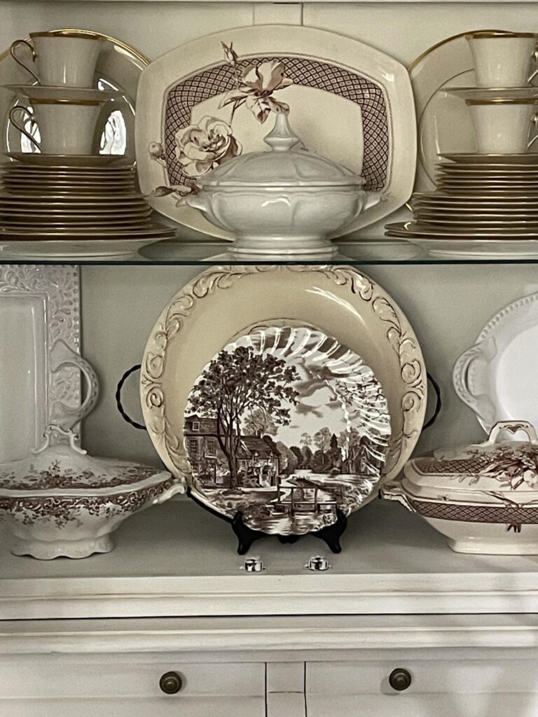 China, ironstone, and brown transferware in a China cabinet. 