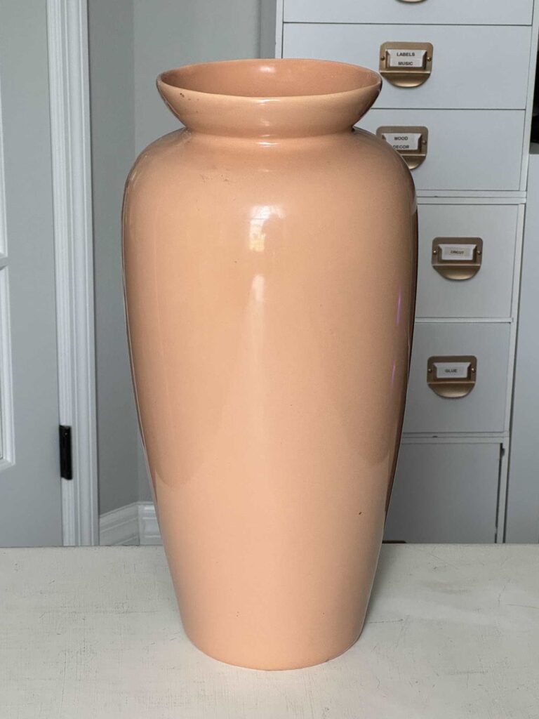 A peach colored ceramic vase. 