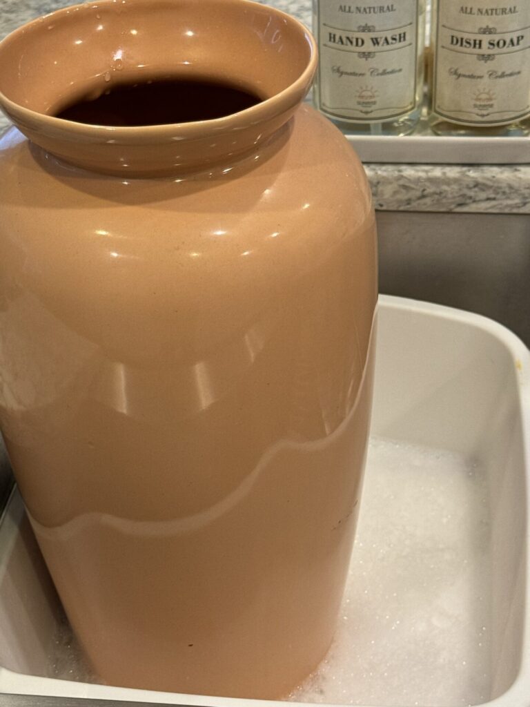 Peach vase being washed with dish soap. 