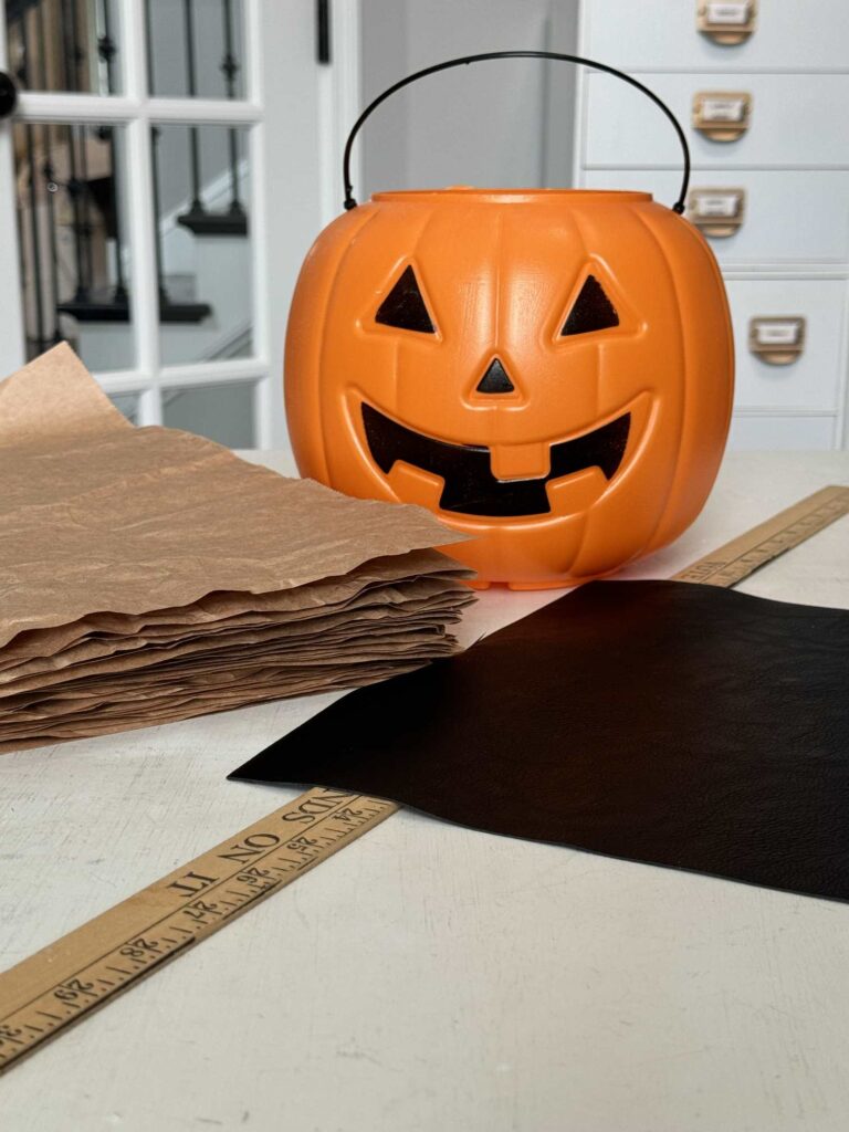 Orange pumpkin pail, packing paper, faux leather, and a yard stick. 