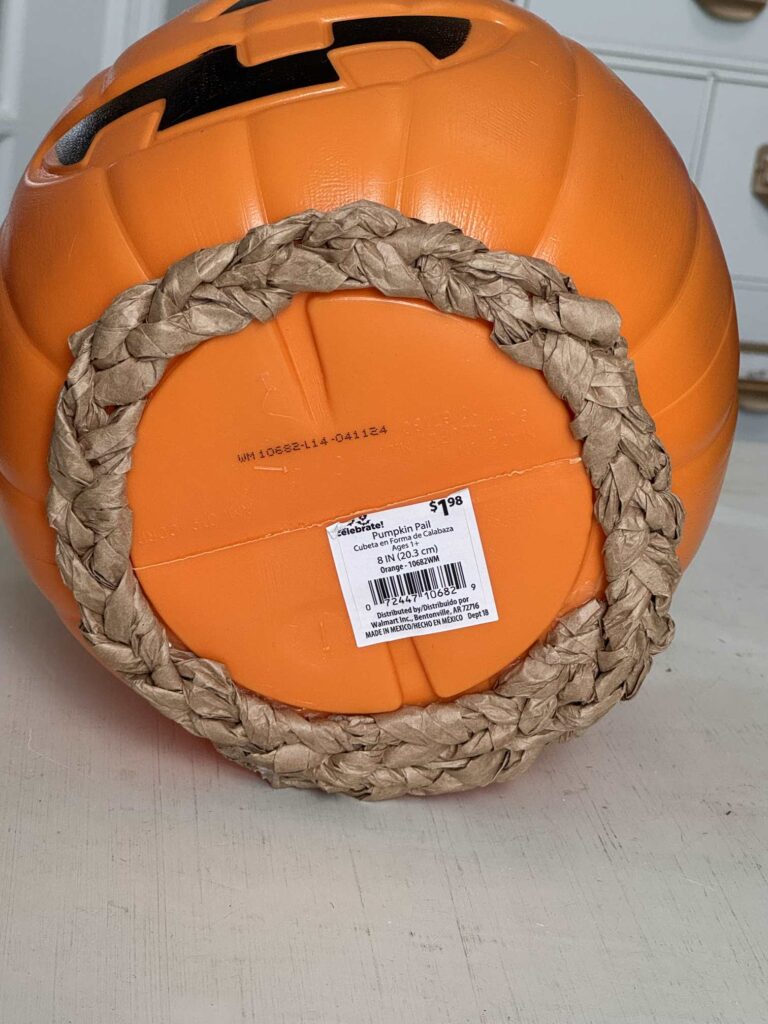 A packing paper braid adhered to the bottom of a pumpkin pail.