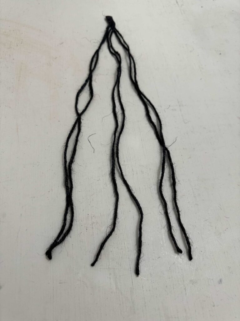 Six strands of black jute twine hot glued together on one end. 