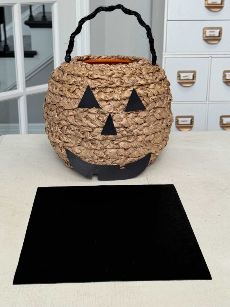 Jack-o-lantern template made out of cardstock. With a piece of leather laying in front of it. 