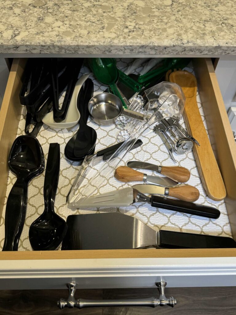 A disorganized drawer of serving utensils. 