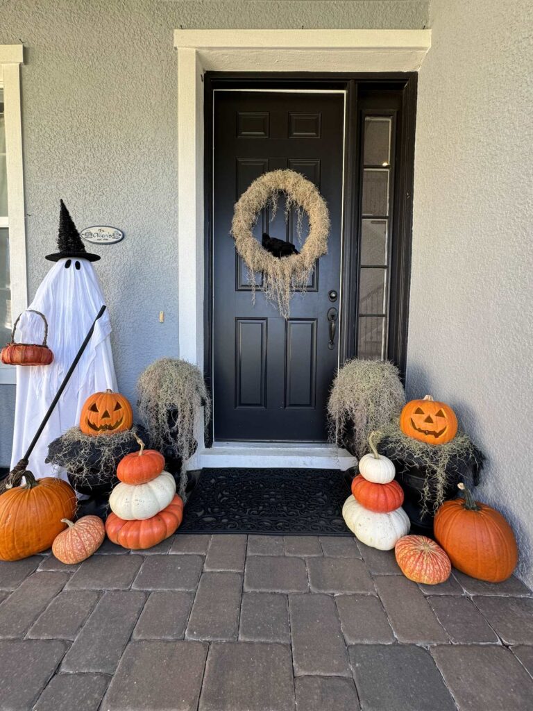 Orange and white pumpkins, a ghost witch, and a crow wreath make perfect Halloween porch decor.