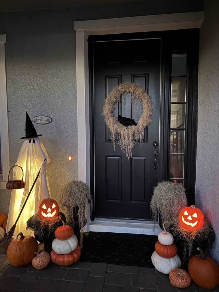 Light-up ghost and two jack-o-lanterns surrounded by pumpkins. 