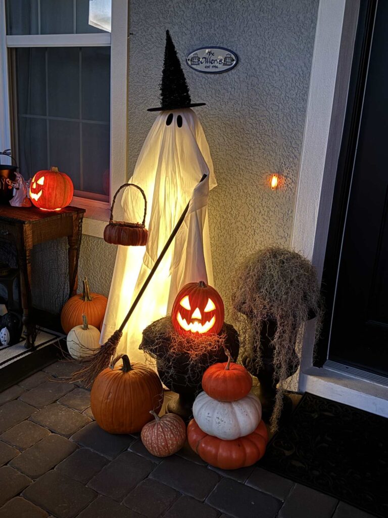 A light-up ghost holding a broom and pumpkin basket. 