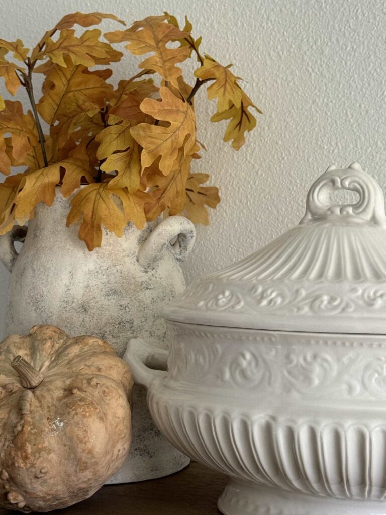 A vase filled with leaves, a soup tureen, and a gourd. 