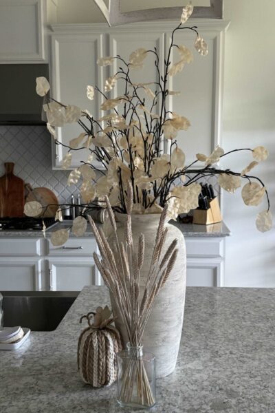 Upcycled vase filled with neutral stems on a kitchen counter.