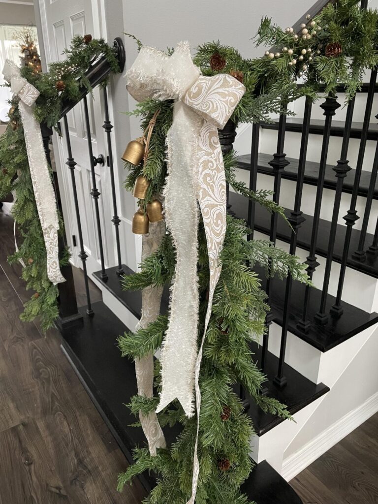 Greenery, bows, and bells hanging on a banister. 